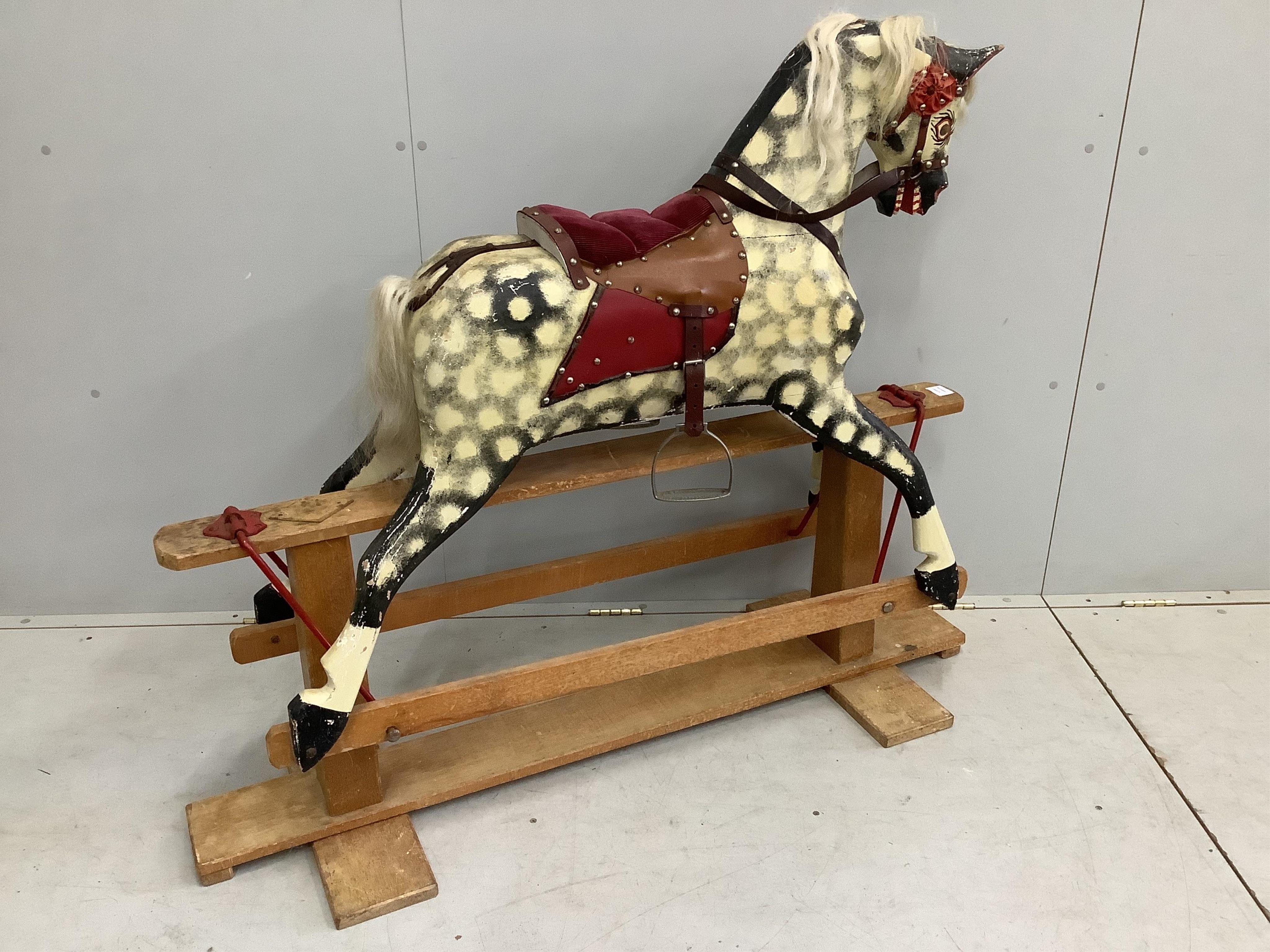 A mid-20th century dapple grey rocking horse, probably by Collinson, with corduroy and leather saddle and painted wooden body, 112cm high, the stand 137cm long. Condition fair, losses to the paint work and notable damage